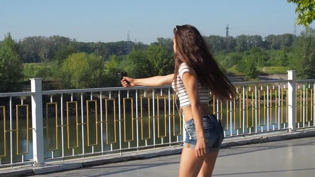 A girl on roller skates shoots herself with a video camera. Beautiful teen girl with video camera.