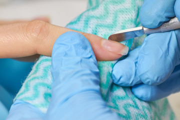 Manicurist cleaning nails to female client. Woman hands in nail salon receiving manicure close up. Young woman is getting manicure in a beauty salon.