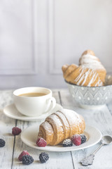 Croissants with fresh berries and a cup of coffee