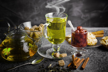 Tea in a cup on a metallic background in a composition with a cookware