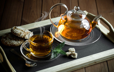 Tea in a cup on a metallic background in a composition with a cookware