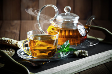 Tea in a cup on a metallic background in a composition with a cookware