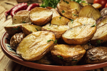 Close up of steaming hot baked potato,Hot buttered jacket baked potatoes,Roasted potato in bowl on wooden table,Oven-baked potatoes with sea salt and rosemary,toasted baked potato strewed with herbs.