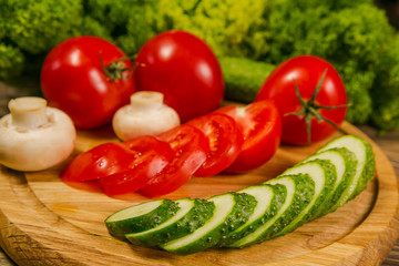 Fresh vegetables. Tomatoes, cucumbers and mushrooms on a wooden board. Delicious vegetarian food. Salad.