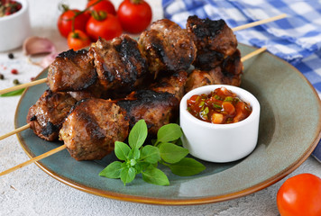 Homemade pork shish kebab with tomato sauce on a concrete background