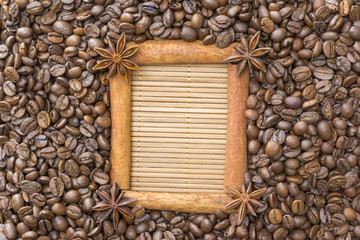 The frame of cinnamon , star anise , around the grain roasted coffee on the background bamboo Mat