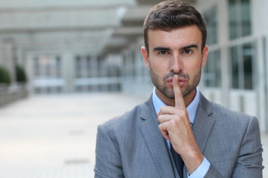 Man using a finger sign to request someone to remain silent