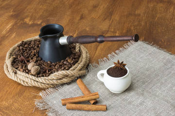 Coffee beans in a ring of hemp, cinnamon,star anise and nutmeg on a background of a wooden table. Roasted coffee bean background close up.