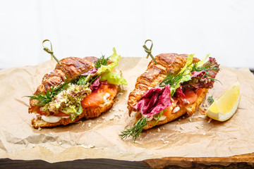 Croissant with salmon and lettuce lies a paper.
