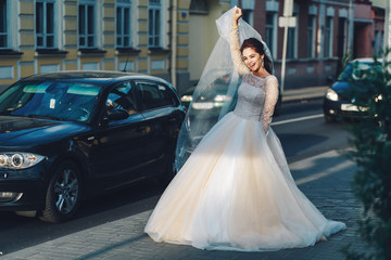 Portrait of a beautiful bride with short dark hair smiling, on a busy street with cars, smiles of natural emotions.