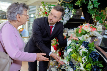 elderly woman buying flowers at funeral service - obrazy, fototapety, plakaty