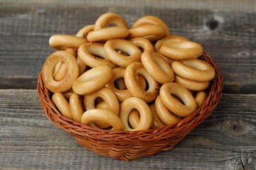 Tasty bagels in basket on wooden table 