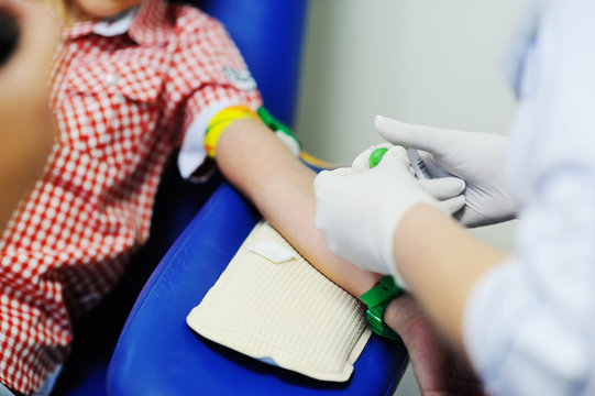a doctor or nurse takes blood from a vein in a child of a boy. Blood chemistry