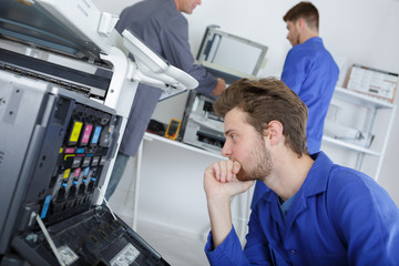 young efficient engineer working on a printer and adjusting components