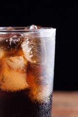 Close up on a cold refreshing soft drink with ice on a dark wooden background
