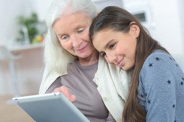 happy grandmother with grand daughter looking at a tablet