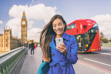 Asian woman using phone walking in London city urban lifestyle. Businesswoman portrait smiling...