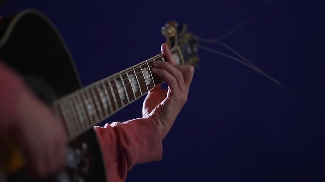Close-up of a guitarist playing Barre chord on acoustic guitar