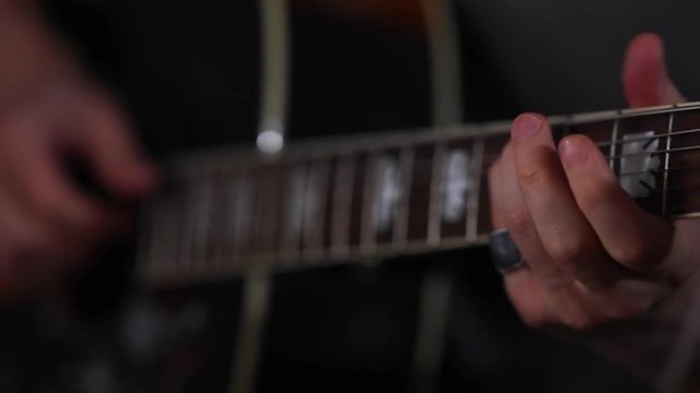 A man plays a fast solo on acoustic guitar close-up of fingers with rings