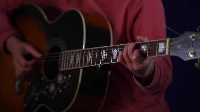 A girl who learns to play acoustic guitar close-up of hands on the strings