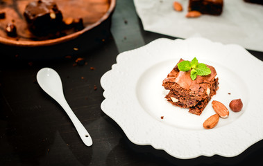 Homemade chocolate brownies on a white porcelain plate on wooden background closeup, top view