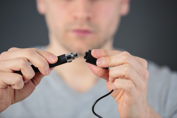 mans hands pluging electronic cigarette