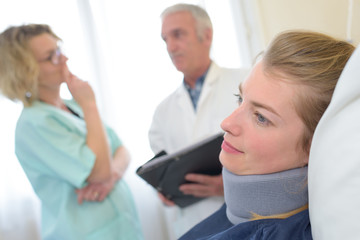 close up female patient wearing neck brace and doctors background