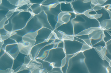 Fototapeta na wymiar Turquoise blue water of swimming pool with sunlight reflecting. Abstract background or backdrop. Leisure summertime tourist activity.