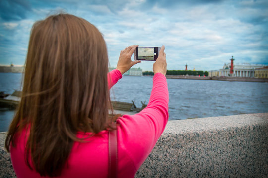 Russia. St. Petersburg. The girl is taking pictures of Vasilievsky Island. White nights in Petersburg.