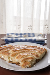 Served balkan burek cheese pie on the plate with silverware on the plate in the background