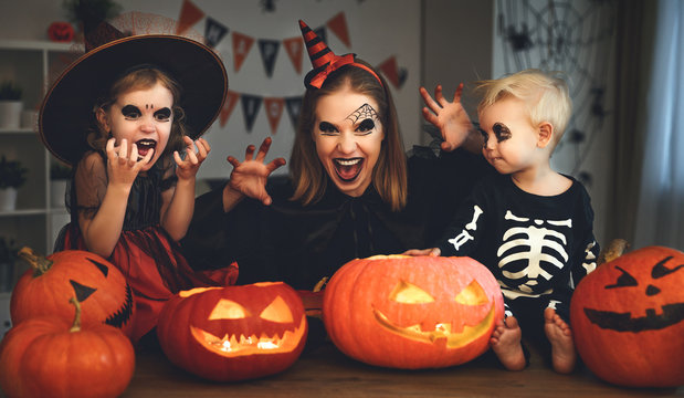 family mother and children in costumes and makeup to halloween with pumpkin in   dark  .