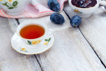 Cup of tea with berry jam and fresh fruits on old wooden table