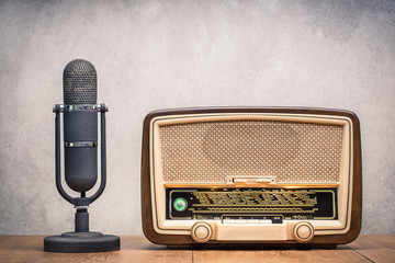 Retro broadcast table radio receiver with green eye light, studio microphone circa 1950 on wooden...