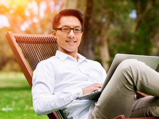Fototapeta premium Young businessman using laptop while sitting outdoors