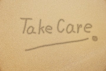 take care handwriting with smiling face on fine sand