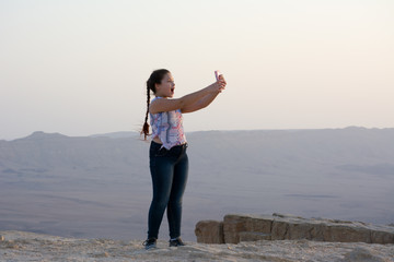 little girl make selfie on the edge of rock crater