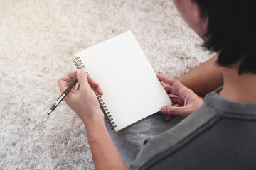 a man holding notebook, blank white page . sitting on white carpet
