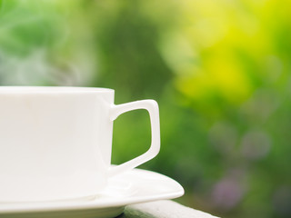 Soft focus of close up coffee cup in garden.