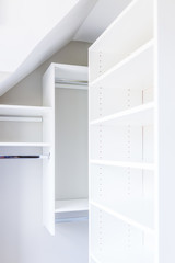 Closeup of modern minimalist white small closet shelves with bright light in staging model house or apartment