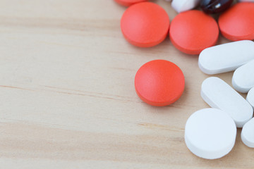 Obraz na płótnie Canvas White, black and red medicine pills on a wooden background.