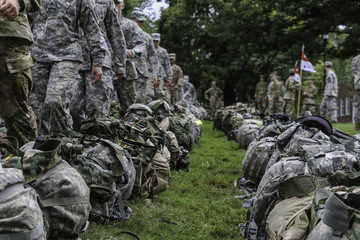 Soldiers marching by backpacks on grass