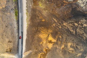 Open road with car driving on travel adventure aerial view of desert landscape for vacation concept. Highway crossing through lava rocks volcanic mountains, nature background in Iceland. - Powered by Adobe