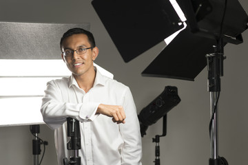 Man in Long Sleeve Shirt Surrounded by Studio Lighting Equipment