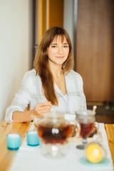 Beautiful little girl having breakfast yogurt with granola and tea in kitchen. People, morning, breakfast and healthy food concept.