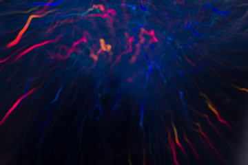 Abstract background of colorful crankles in motion on black. Bokeh of defocused curves, blurred neon blue, orange and purple leds, festive backdrop of fireworks, holidays and celebrations