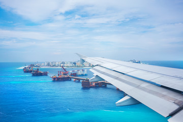 Scenery from airplane 's window before landing ,  seeing wing of airplane and Malé , capital of  Republic of Maldives located in the Indian Ocean