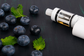 white electronic cigarette on a dark table, next to a scattered berry