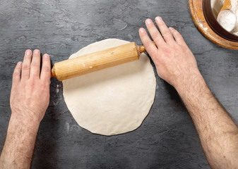 Man preparing pizza dough in bakery, top view