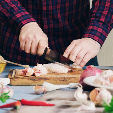 Man cooking chicken wings with cranberry sauce in home kitchen