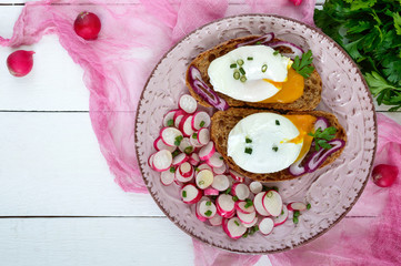 Egg poached on a piece of cereal ciabatta with a radish salad on a plate. A useful sandwich. Proper nutrition. Breakfast.